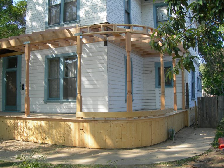A wooden porch on the side of a house.