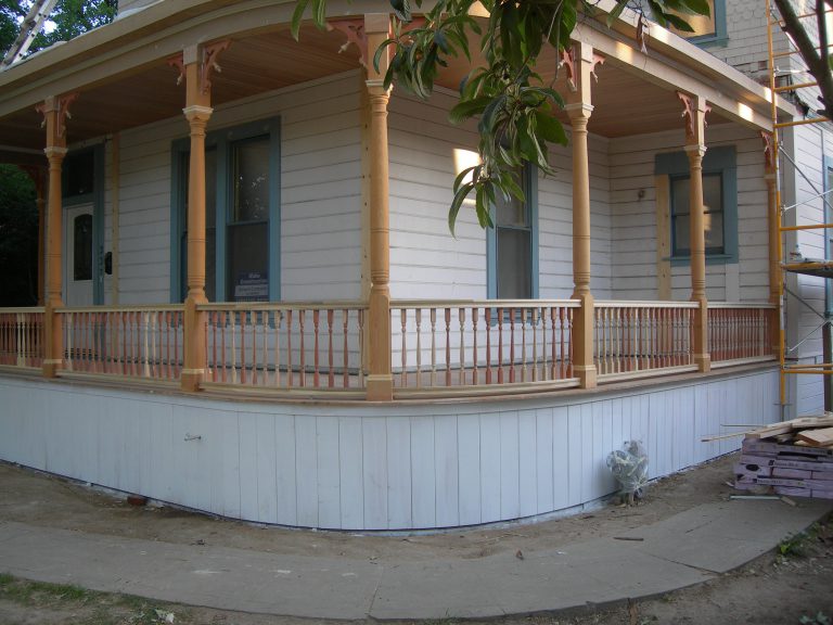 A wooden porch on the side of a house.