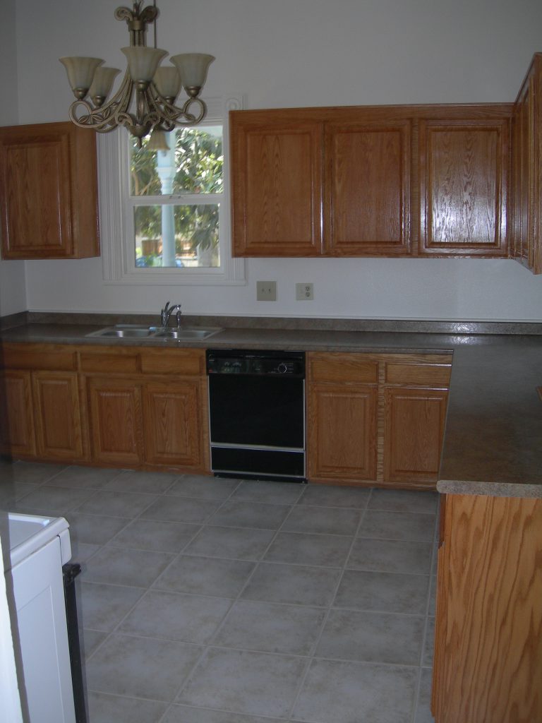 A kitchen with wooden cabinets and tile floors.