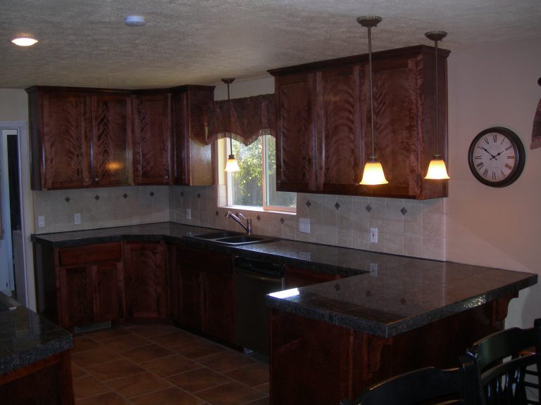 A kitchen with brown cabinets and a black counter top.