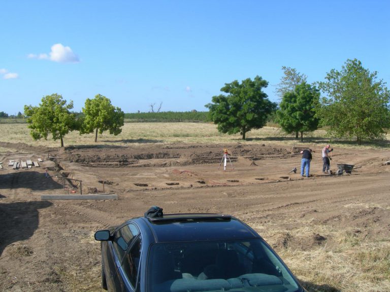 A black car is parked in the dirt.