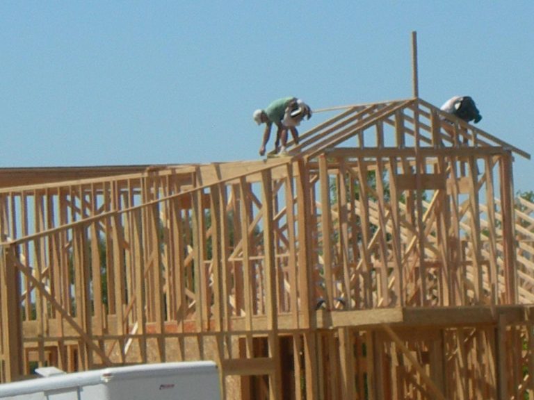 Two men working on the roof of a house.