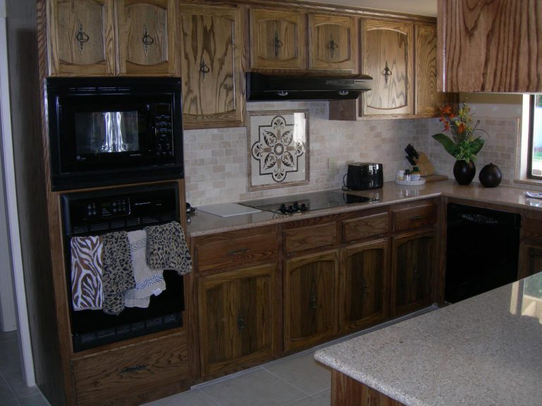A kitchen with brown cabinets and a microwave oven.