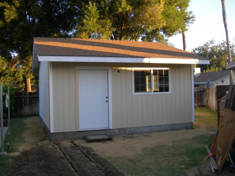 A tan shed with a white door.