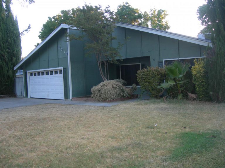 A green house with a garage in front of it.