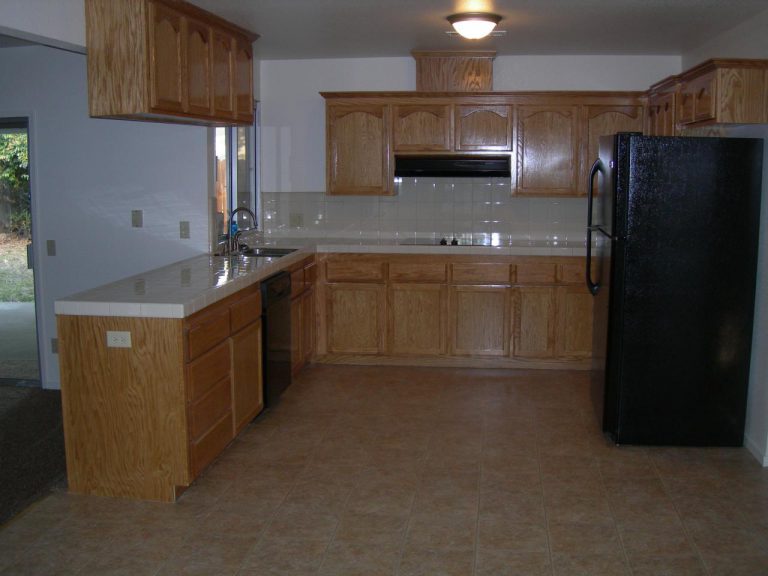 A kitchen with wooden cabinets and a black refrigerator.