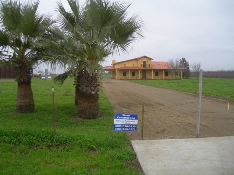 A dirt road in front of a house.