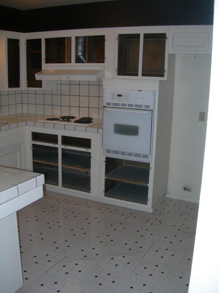 A white kitchen with black and white tiled floors.