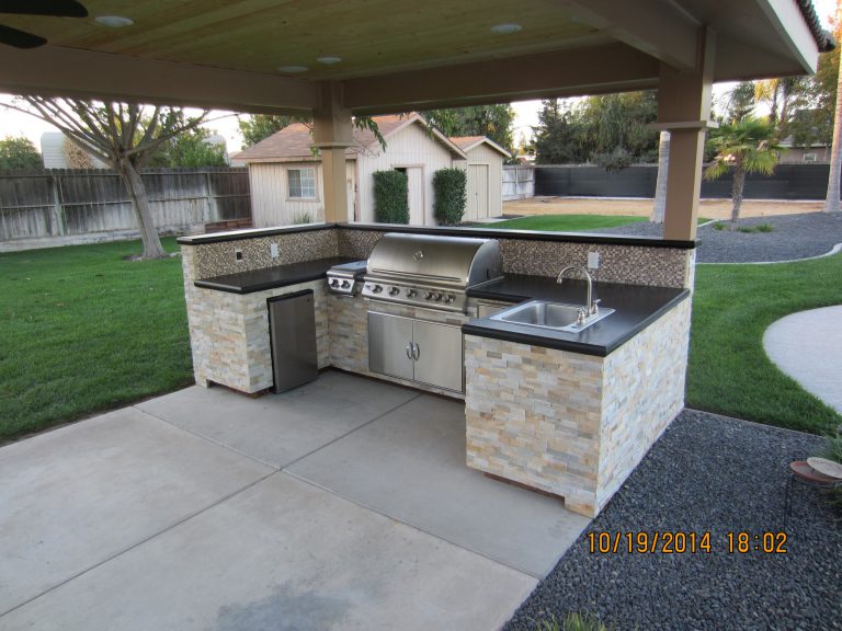 An outdoor kitchen with a grill and sink.