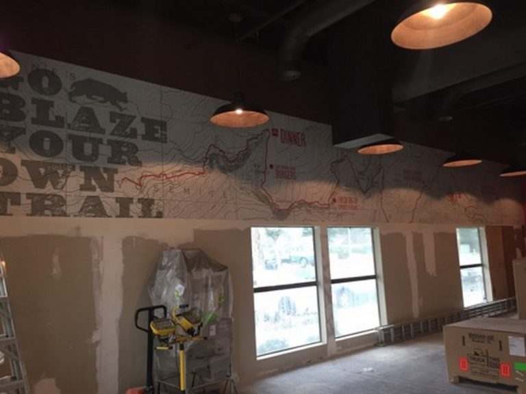 A mural is being painted on a wall in a restaurant.