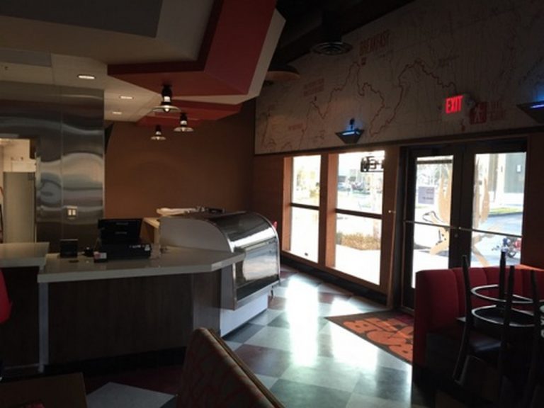 The inside of a restaurant with a counter and chairs.