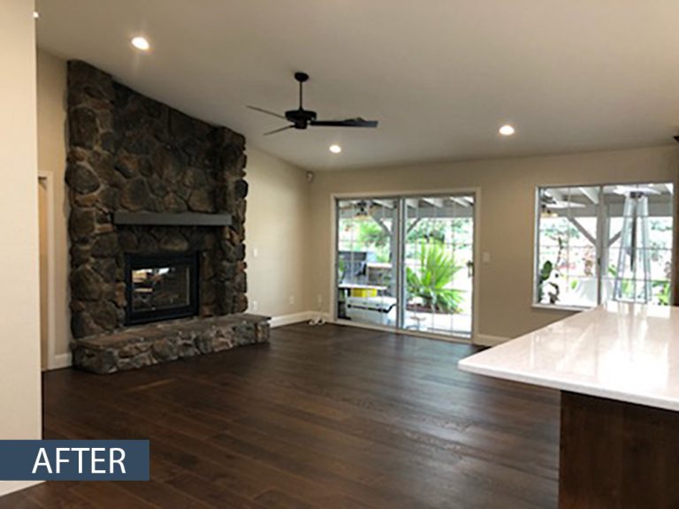 An empty living room with hardwood floors and a fireplace.