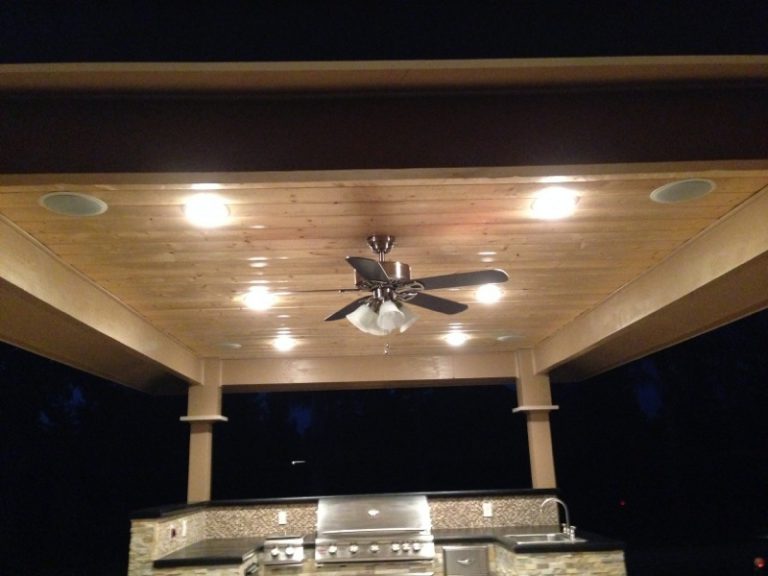 An outdoor kitchen with a ceiling fan and lights.