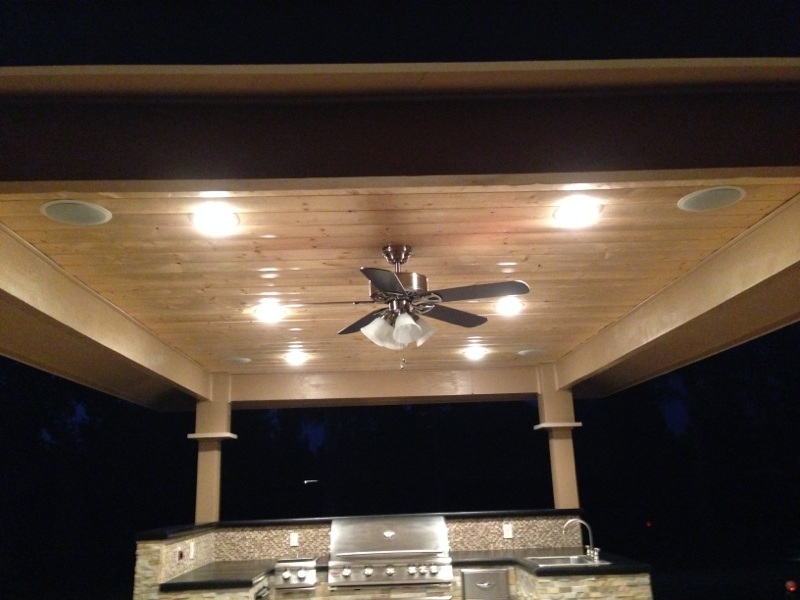 An outdoor kitchen with a ceiling fan and lights.