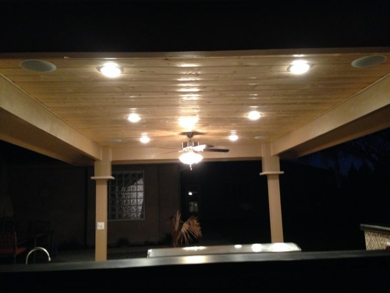A covered patio with a ceiling fan and lights.