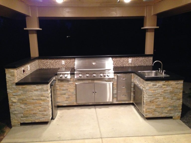 An outdoor kitchen with a grill and sink.