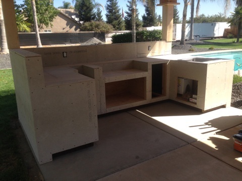 An outdoor kitchen is being built in a backyard.