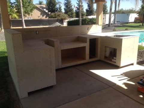 An outdoor kitchen is being built in a backyard.