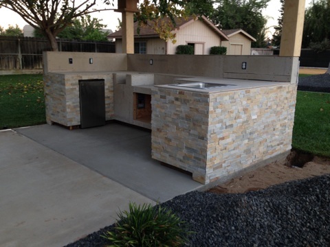 An outdoor kitchen with a sink and counter top.