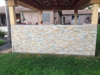 A stone patio with a pergola in the backyard.