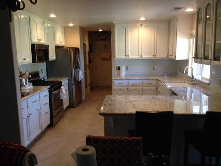 A kitchen with white cabinets and granite counter tops.