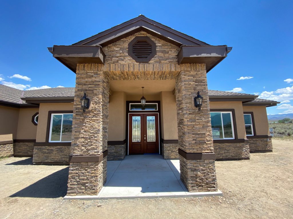 A home with a front door and a stone wall.